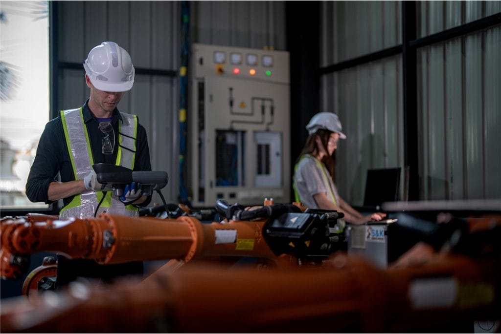 Two HVAC technicians working together on an air conditioning unit, using tools and equipment to perform maintenance or repairs.