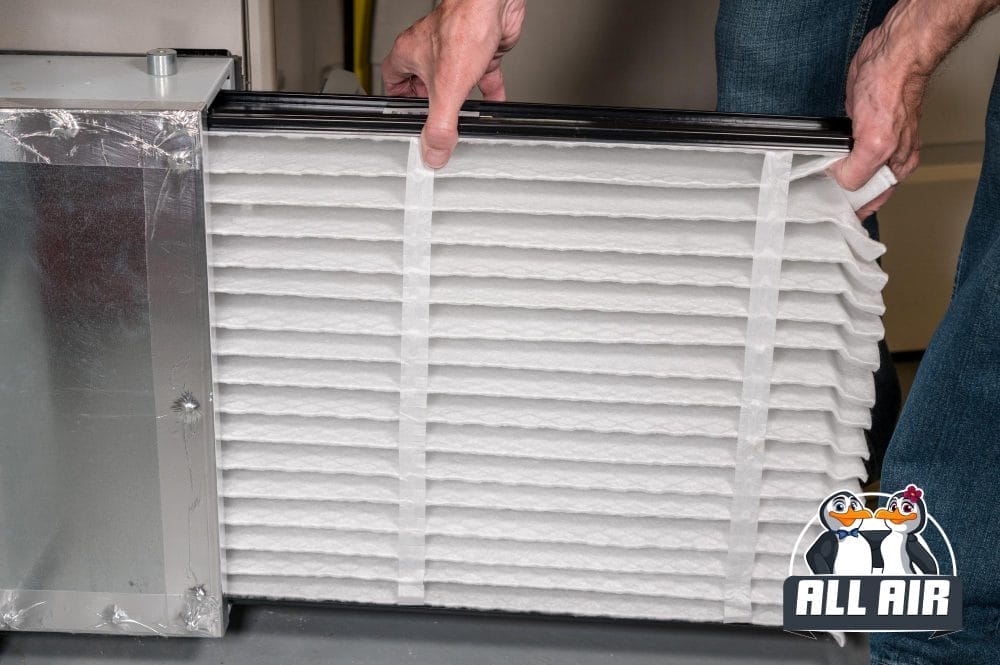 Technician replacing a dirty heating system air filter to improve indoor air quality and system efficiency