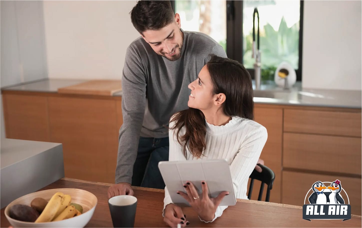 Couple discussing a decision at home, woman holding a tablet at the table