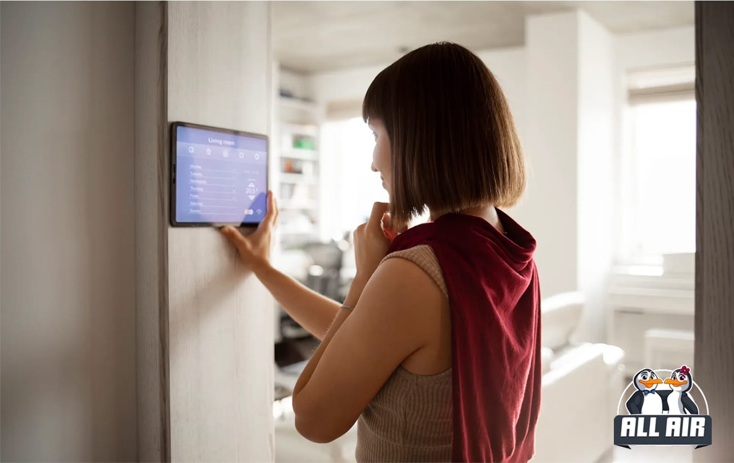 Woman adjusting room temperature on wall-mounted smart thermostat