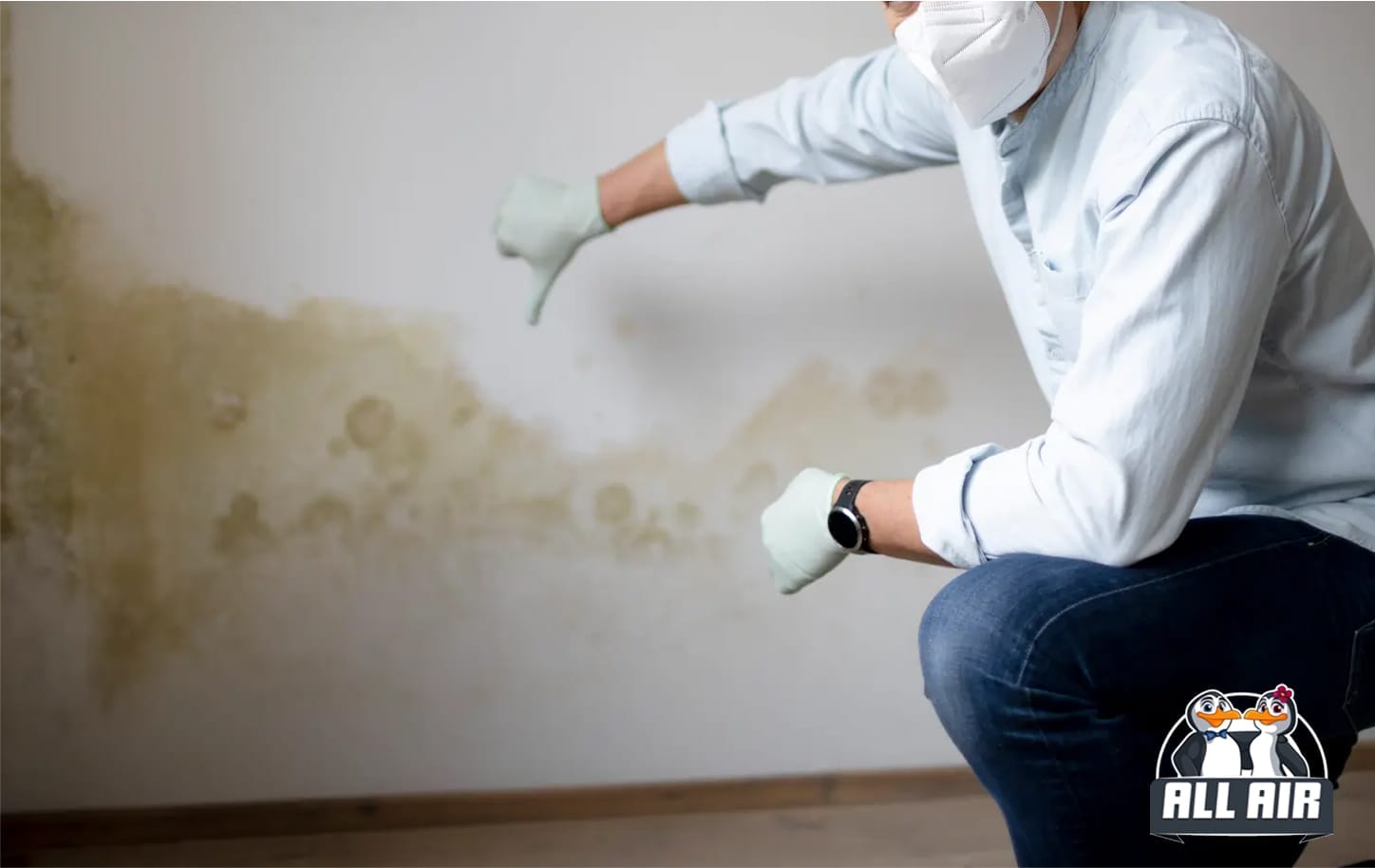 Man in semi-squat giving thumbs down gesture toward moldy wall at home