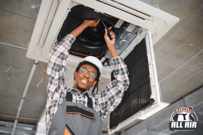 HVAC technician cleaning ceiling air conditioning vent to improve indoor air quality